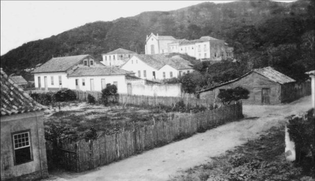 Igreja matriz de Garopaba no tempo do Pe. Rafael Faraco, ainda sem a torre. Ao lado, a casa de dois andares que foi sua residência.